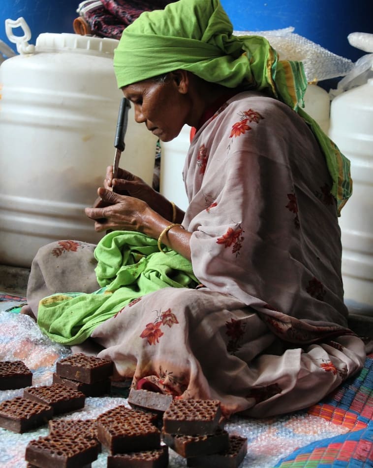 Village woman handcrafting beeswax soaps at Last Forest Enterprises
